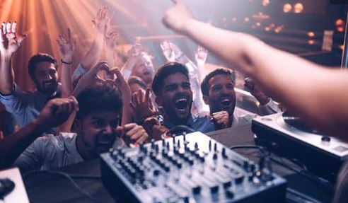 a couple of guys in front of a DJ booth, very enthusiastic.
